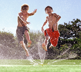 Kids Jumping Through Sprinkler